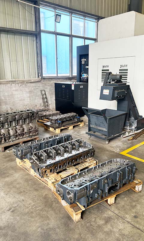 Cylinder heads on pallets beside a CNC machining center