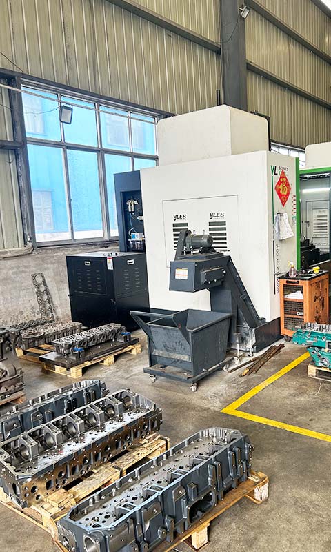 Cylinder heads on pallets beside a CNC machining center